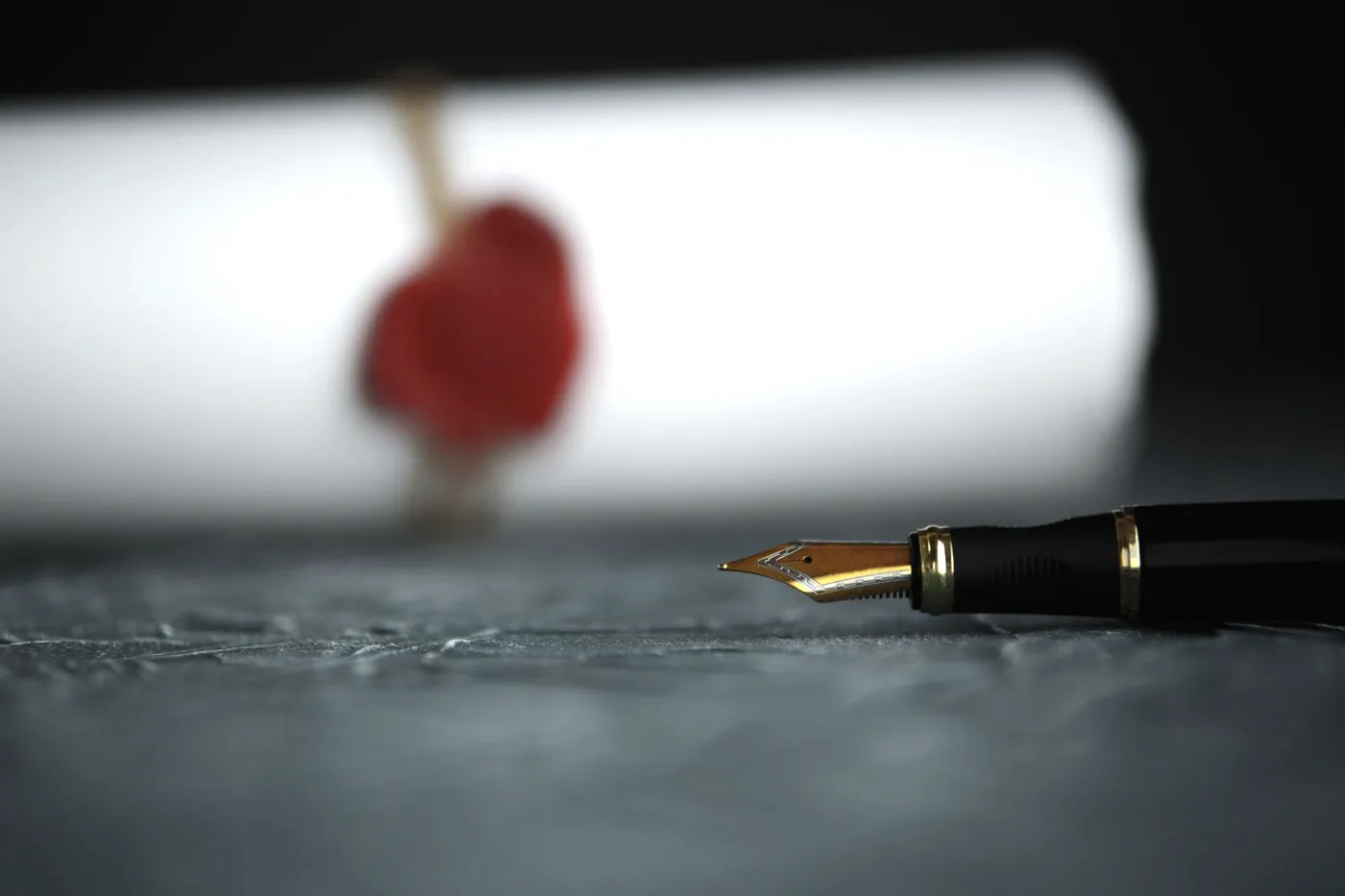 Opgerolde, met lakzegel gesloten notariële akte met vulpen op een donkere tafel